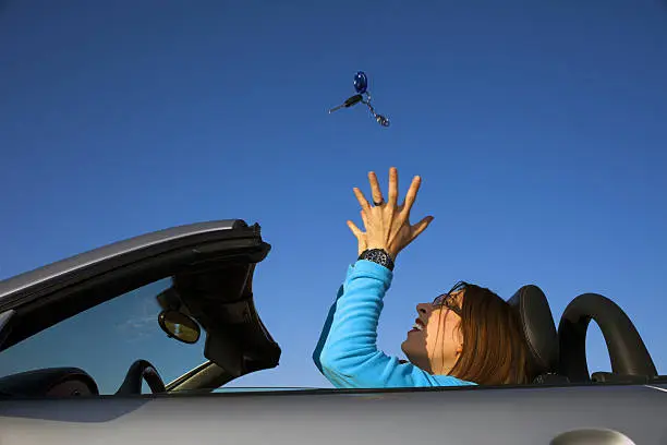 a woman throwing car jey ring in the air